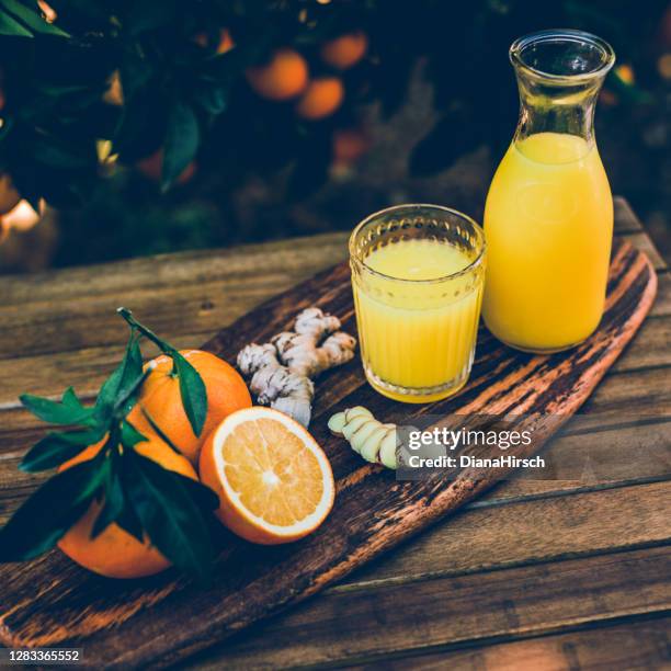 frisch gepresster orangensaft aus unbehandelten bio-orangen und ingwerwurzel aus dem eigenen garten im instagram-stil - fruchtsaft stock-fotos und bilder