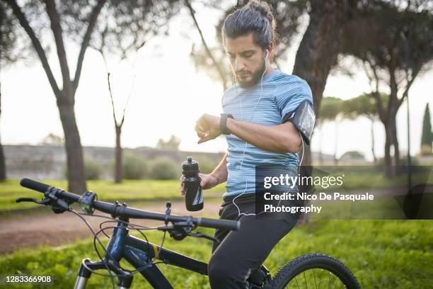 cyclist checking smart watch - players to watch stock-fotos und bilder
