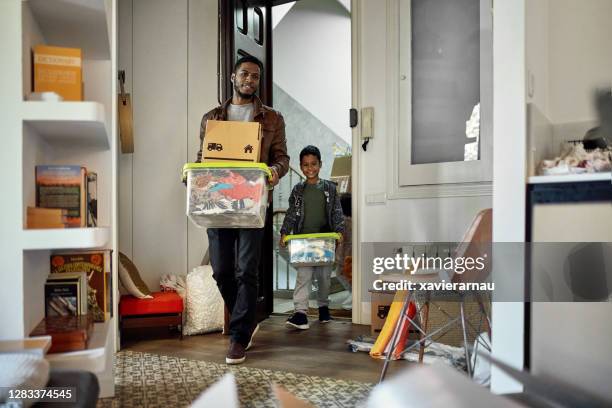 young boy following father into new apartment on moving day - man boxes moving home stock pictures, royalty-free photos & images