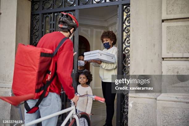 pizza delivery to afro-caribbean family with two children - take away food courier stock pictures, royalty-free photos & images