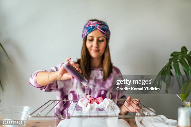 giovane donna fare cravatta tintura vestiti in salotto - dyes foto e immagini stock