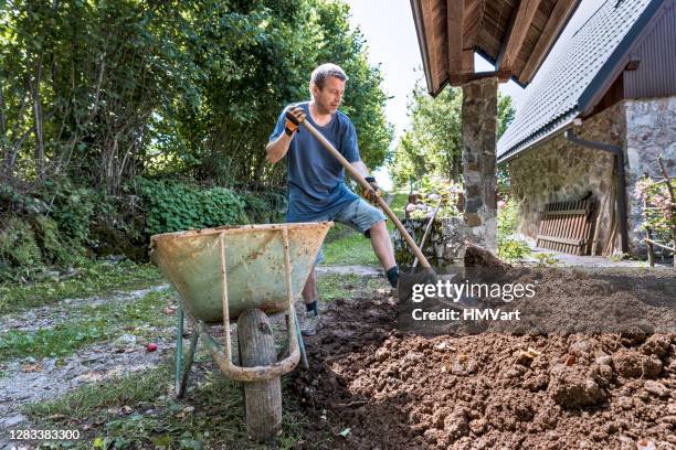 man removing the soil from the house entrance to prepare a new yard area - digging stock pictures, royalty-free photos & images