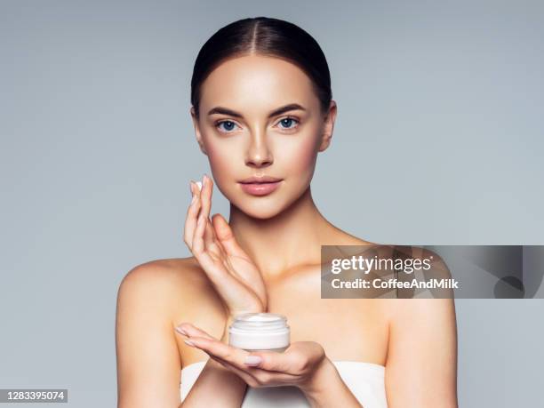 leuke vrouw die room toepast op haar gezicht - schoonheidsspecialist stockfoto's en -beelden