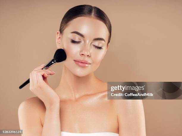 mooie jonge vrouw die stichtingspoeder toepast - applying make up stockfoto's en -beelden