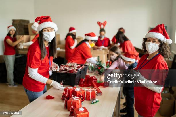 frauen ehrenamtlich durch vorbereitung von weihnachtsgeschenken für arme menschen in zeiten der pandemie - chocolate pack stock-fotos und bilder