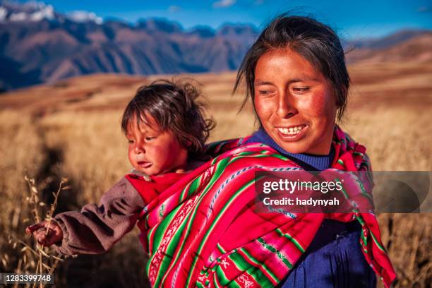 donna peruviana che porta il suo bambino sulla schiena vicino a cuzco - cordigliera delle ande foto e immagini stock