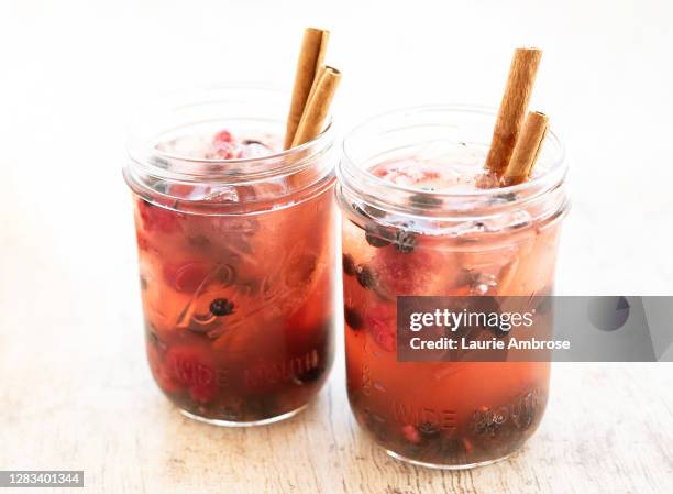 fall cinnamon and berry drink in glass jar sitting on wooden tabletop - cocktail and mocktail stockfoto's en -beelden