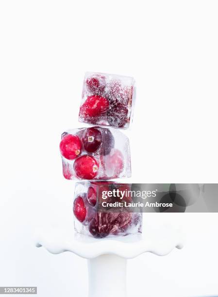 a stack of ripe red cranberries frozen in ice cubes - eiswürfel stock-fotos und bilder