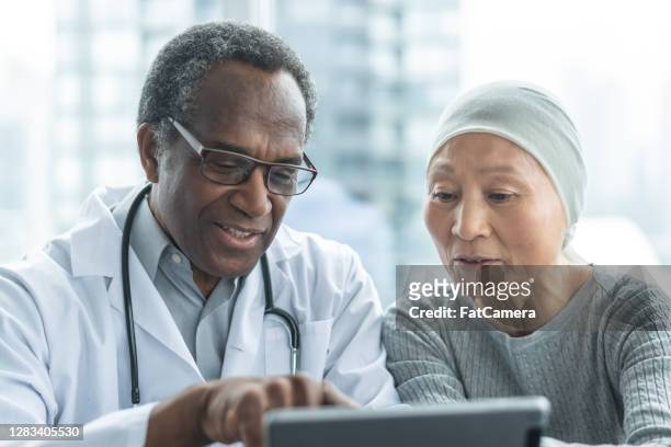 woman with cancer reviews test results with doctor - leukemia stock pictures, royalty-free photos & images