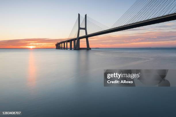 urban landscape. background with colourful sunrise on the lisbon bridge. the vasco da gama bridge is a landmark, and one of the longest bridges in the world. - vasco da gama stock-fotos und bilder