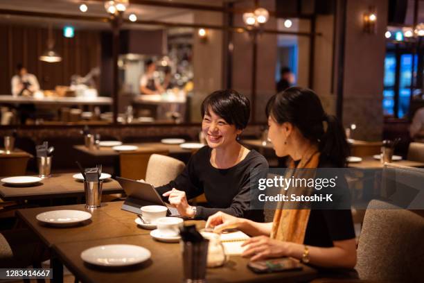 japanese women having business discussion in elegant cafe - japanese restaurant stock pictures, royalty-free photos & images