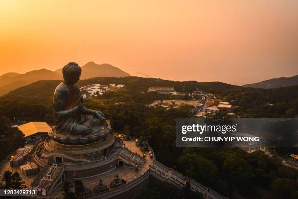 drone view of the big buddha is lit in the evening - lantau stock pictures, royalty-free photos & images