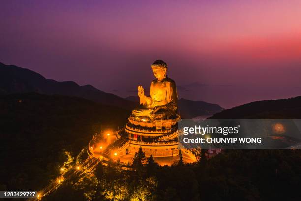 drone view of the big buddha is lit in the evening - buddhist goddess stock pictures, royalty-free photos & images