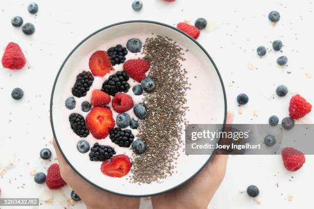 hands holding a healthy smoothie bowl mit granola und frischem obst - chiasamen stock-fotos und bilder