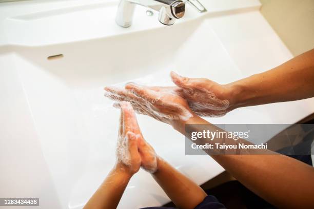 father and son washing their hands together in the bathroom - child washing hands stock pictures, royalty-free photos & images