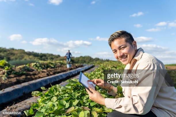 young farmer with digital tablet smiling in the fields. smart farming. - n tech stock pictures, royalty-free photos & images