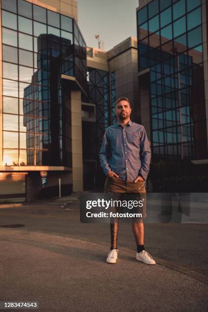 full lenght of serious man with challenged mobility standing in front of building - calf human leg stock pictures, royalty-free photos & images