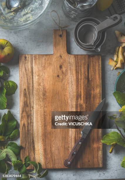 empty wooden rustic cutting board background on rustic table with fresh apples on branches, kitchen utensils and bake tools - cutting board stock pictures, royalty-free photos & images