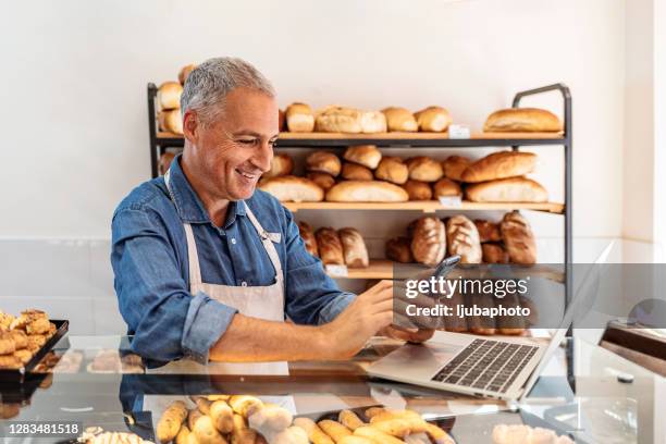 rijpe mens die laptop voor online bedrijfsorde gebruikt - bakery stockfoto's en -beelden