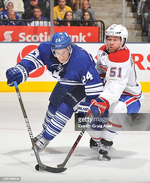 John-Michael Liles of the Toronto Maple Leafs battles for the puck with David Desharnais of the Montreal Canadiens during NHL game action October 6,...
