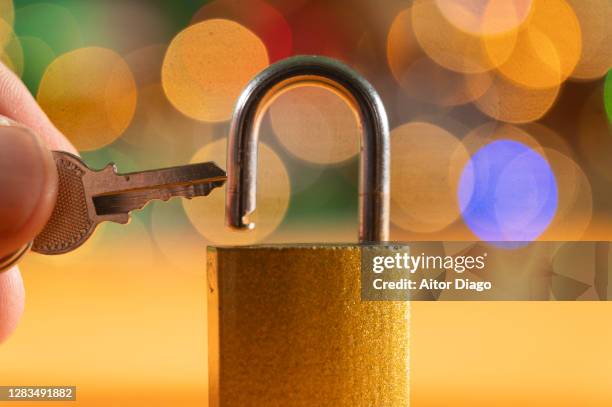 someone is holding a key to a padlock. background with colorful lights. - open prison cell stock pictures, royalty-free photos & images