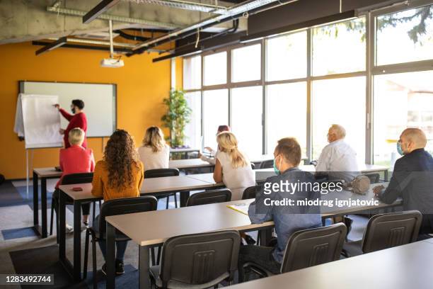 business people listening to presenter during business conference in convention center - adult stock pictures, royalty-free photos & images