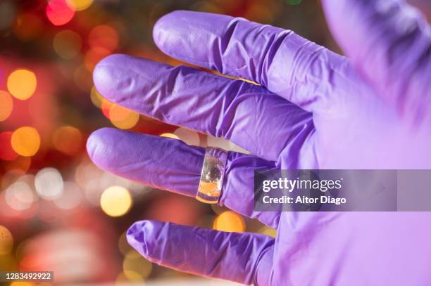 person´s hand with protection wearing a ring in heart finger. in the background there is a decorated christmas tree. - unrequited love stock pictures, royalty-free photos & images