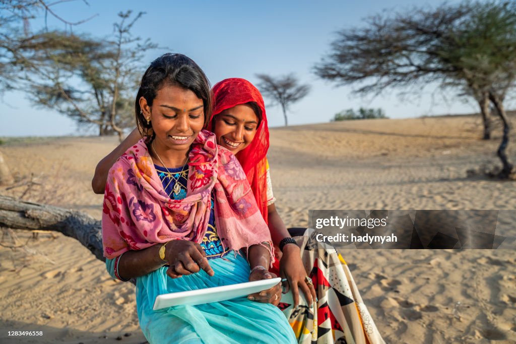 Happy Gypsy Indian girls using digital tablet, India