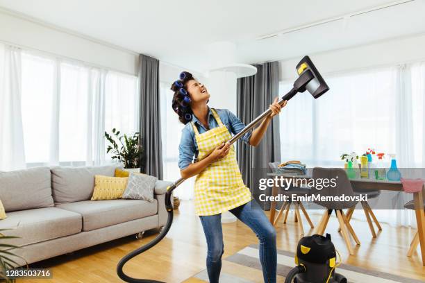 woman holding a vacuum cleaner like a guitar and singing - house cleaning stock pictures, royalty-free photos & images