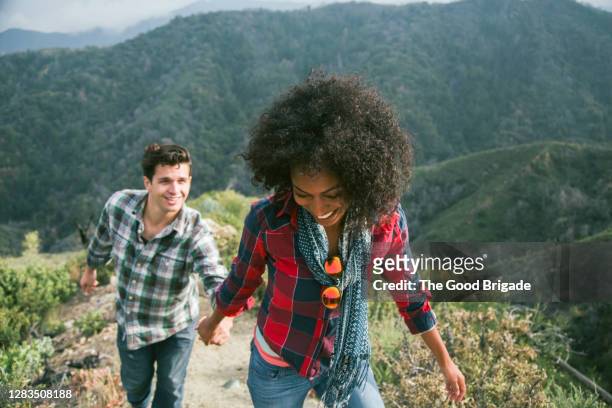 young woman leading boyfriend up a mountain trail - black man plaid shirt stock pictures, royalty-free photos & images