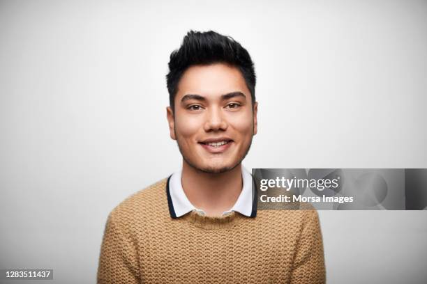 smiling mixed race male student against white background - mixed race man standing studio stockfoto's en -beelden
