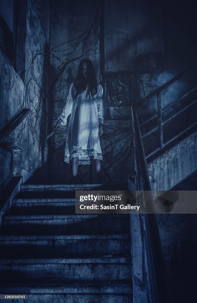 Scary ghost woman with knife in hand and long hair in haunted house