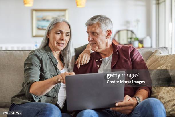 reifes paar mit laptop auf dem sofa zu hause - couple 50 55 laptop stock-fotos und bilder