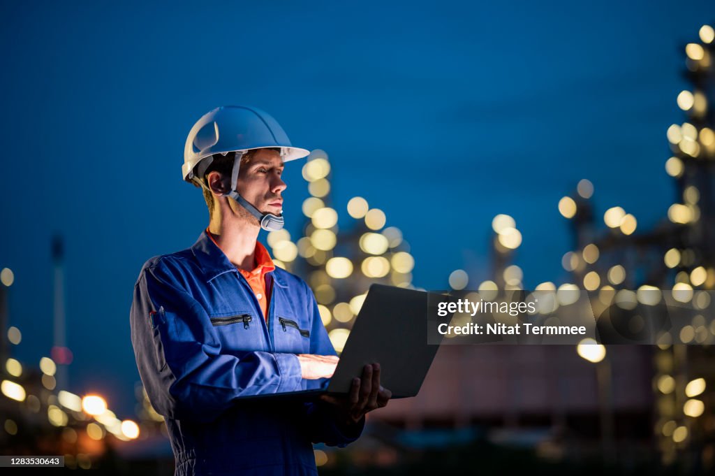 Sustainable, Efficient energy for future. Petroleum Industry Engineer working with laptop in refinery of Oil and Gas refinery.