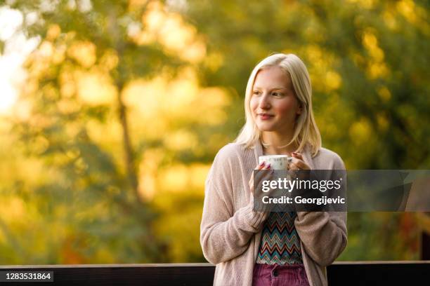 feliz jovencita bebiendo café en el jardín - té terraza fotografías e imágenes de stock