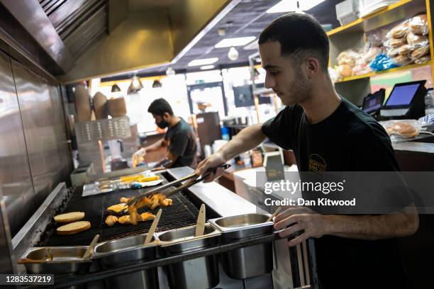 Worker cooks food at 'Meaty Buns' restaurant on November 02, 2020 in London, United Kingdom. The outlet will be moving back to takeaway only from...