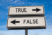 True vs false. White two street signs with arrow on metal pole with word. Directional road. Crossroads Road Sign, Two Arrow. Blue sky background. Two way road sign with text.