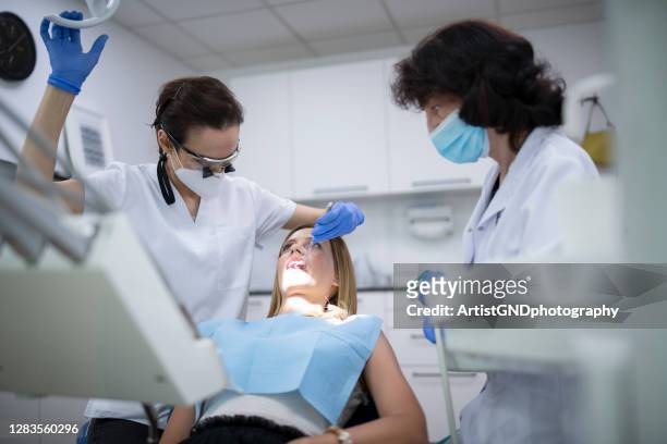 dentiste féminine professionnelle et son assistant travaillant sur le patient dans la clinique dentaire. - bridge stock photos et images de collection