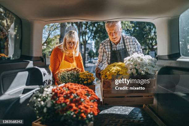 couple unloading crates of fresh flowers from car trunk - unloading stock pictures, royalty-free photos & images