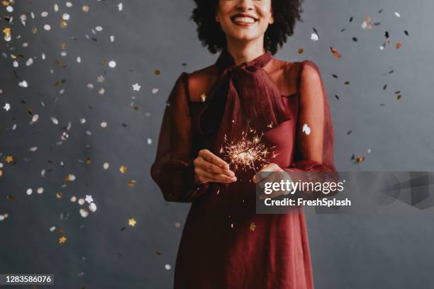 portrait of an anonymous smiling woman in a festive red dress holding sparklers, celebration concept - silver dress imagens e fotografias de stock