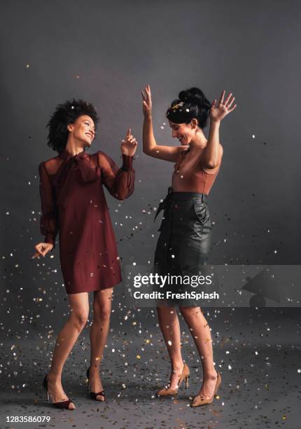 bailando en confeti: dos mujeres elegantes bailando juntas en una fiesta (studio shot, copy space) - silver dress fotografías e imágenes de stock