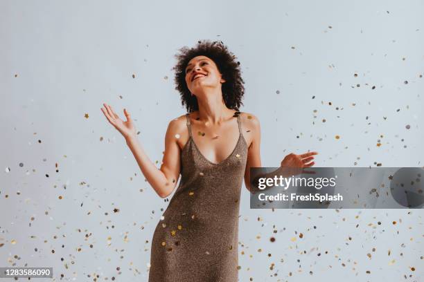 happy woman in a gold dress dancing under confetti - vestido cinzento imagens e fotografias de stock