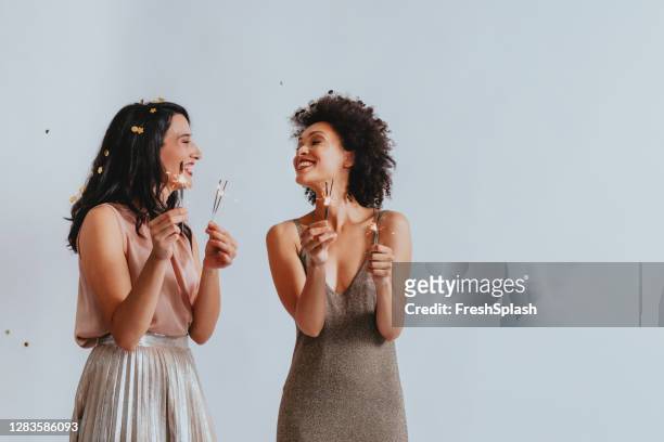 studio shot of two happy women having fun playing with sparklers (copy space) - friends studio shot stock pictures, royalty-free photos & images