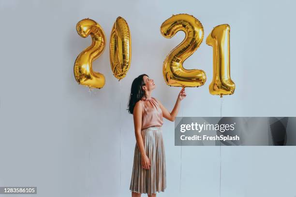 beautiful woman at a new year's party: playing with golden balloons (studio shot) - 2021 balloon stock pictures, royalty-free photos & images