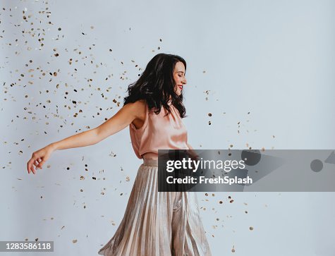 Studio Shopt of a Beautiful Smiling Elegant Woman Dancing Showered With Confetti Studio Shopt of a Beautiful Smiling Elegant Woman Dancing Showered With Confetti