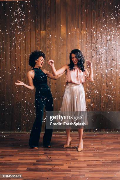 party time: two beautiful women dancing in confetti rain, feeling festive concept - white people dancing photos et images de collection