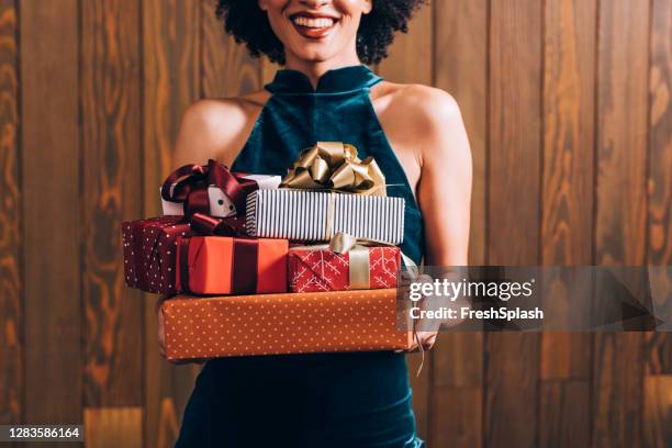 merry christmas: a n anonymous smiling elegant african american woman holding a pile of presents in her hands, a close up - christmas gift stock pictures, royalty-free photos & images