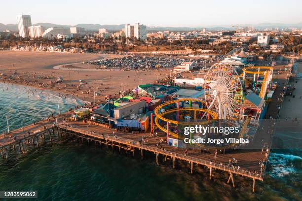 santa monica pier bei sonnenuntergang mit lichtern im pazifischen ozean reflektiert - santa monica pier stock-fotos und bilder