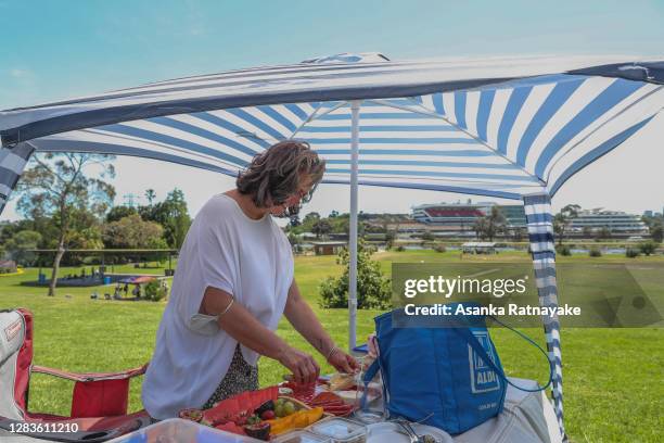 Woman prepares food for a picnic at Footscray Park, one of the few vantage spots to provide a view of the Melbourne cup horse racing at Flemington...
