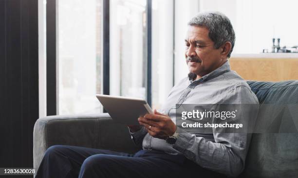 life looks a lot more interesting online - mature man using digital tablet stock pictures, royalty-free photos & images